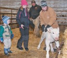 Siblings Hinton, left, Halle and Hunter Herback help a newborn Charolais calf stand up in the birthing barn, as their father, Velon, looks on. | Karen Morrison photo