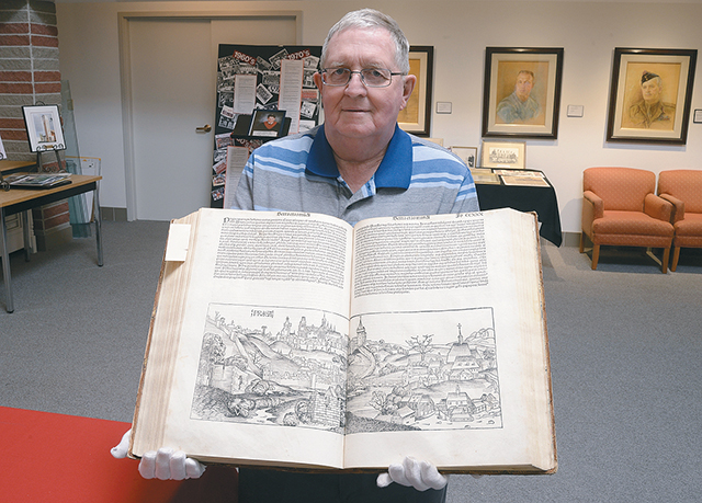 Archivist Gerry Scheibel, holds the Nuremberg Chronicle dating to 1493. | Arlene & Robin Karpan, photo.